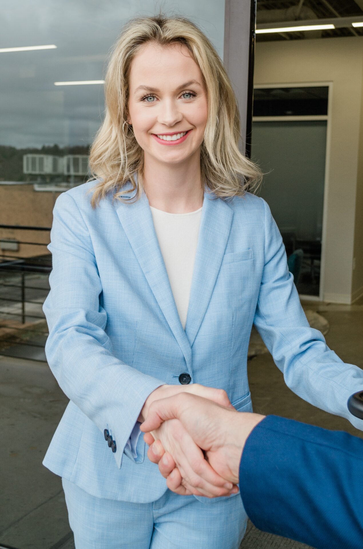 A professional woman wearing a gray suit and white shirt, exuding confidence and elegance.